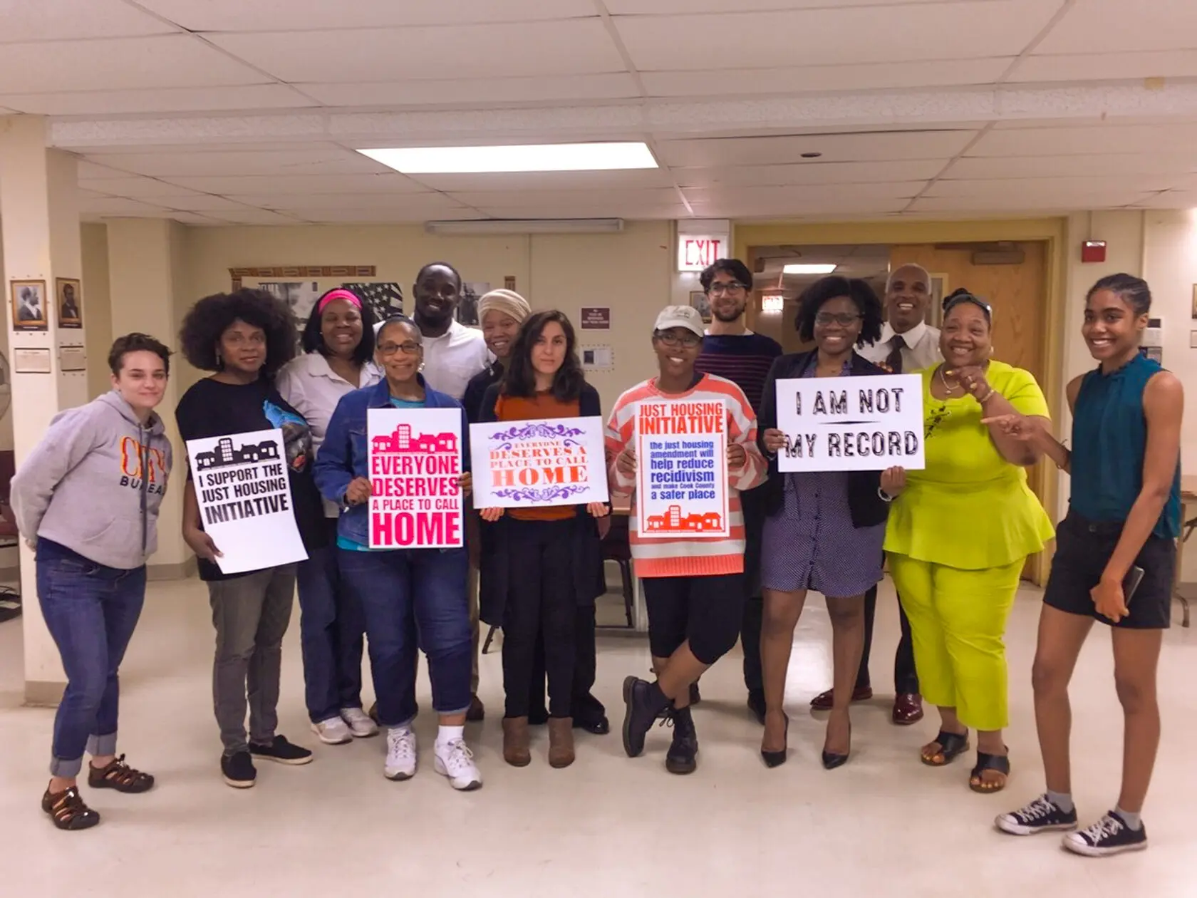 A group holds signs supporting the Just Housing Initiative and the right to housing