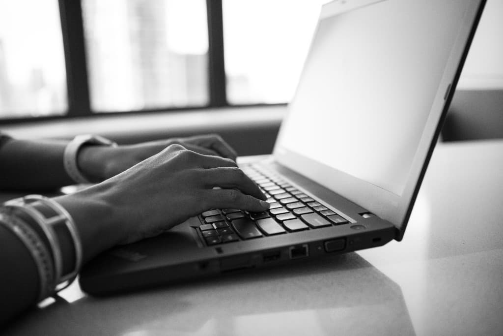Hands typing on a laptop